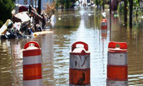 orange blockade barrels float down a flooded city street