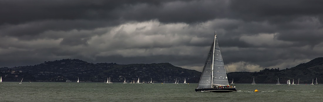 Sailboats on a lake with heavy dark clouds overhead.