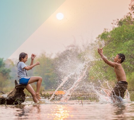 Image shows children playing and splashing in a river