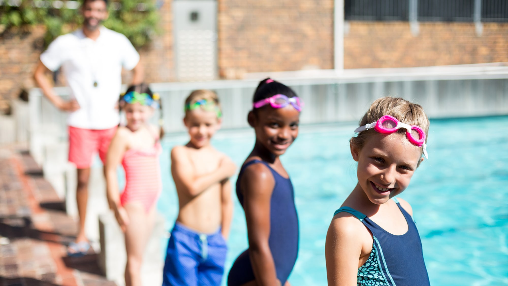 Children at an outdoor swimming lesson with adult swim instructor.
