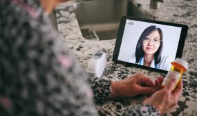 photo of patient video chatting with a doctor while holding medication