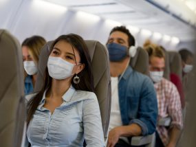 Travel landing - Woman traveling by plane wearing a facemask