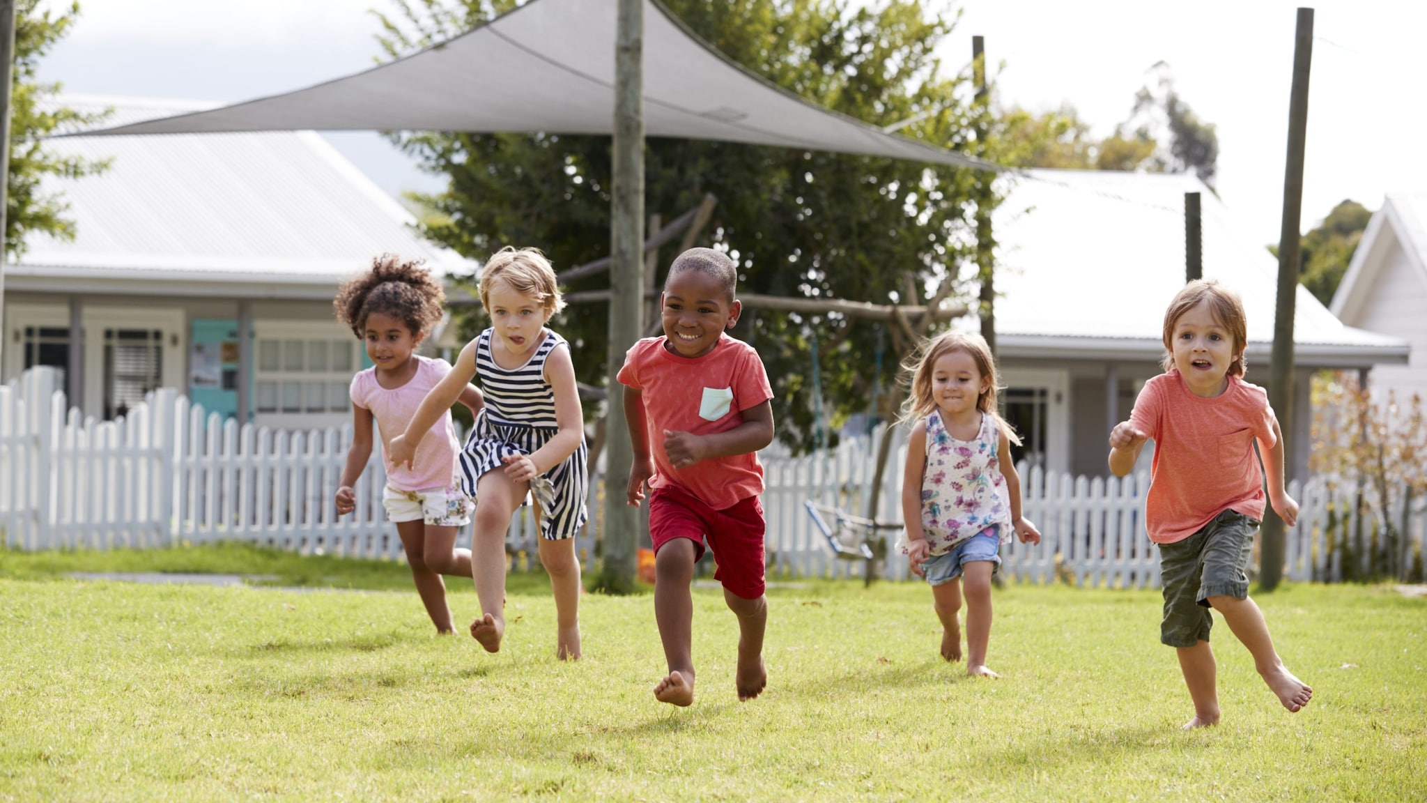 Children of different races smiling and running in an open field.