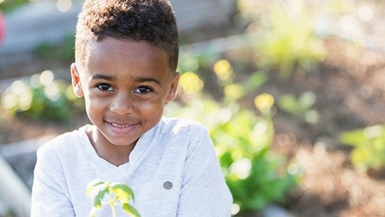Child smiling and holding a plant