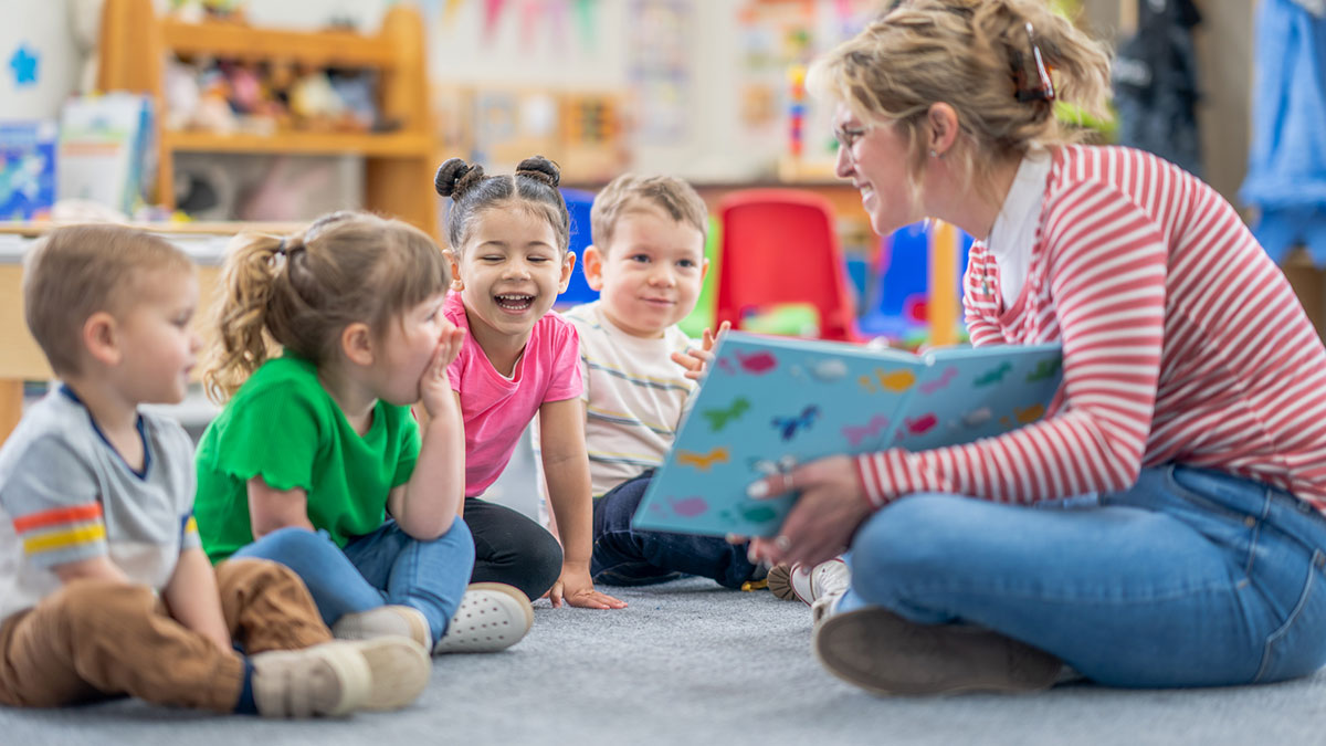 Early educator reading a book to her young students.