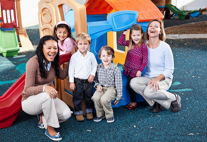 Preschoolers on playground with teachers