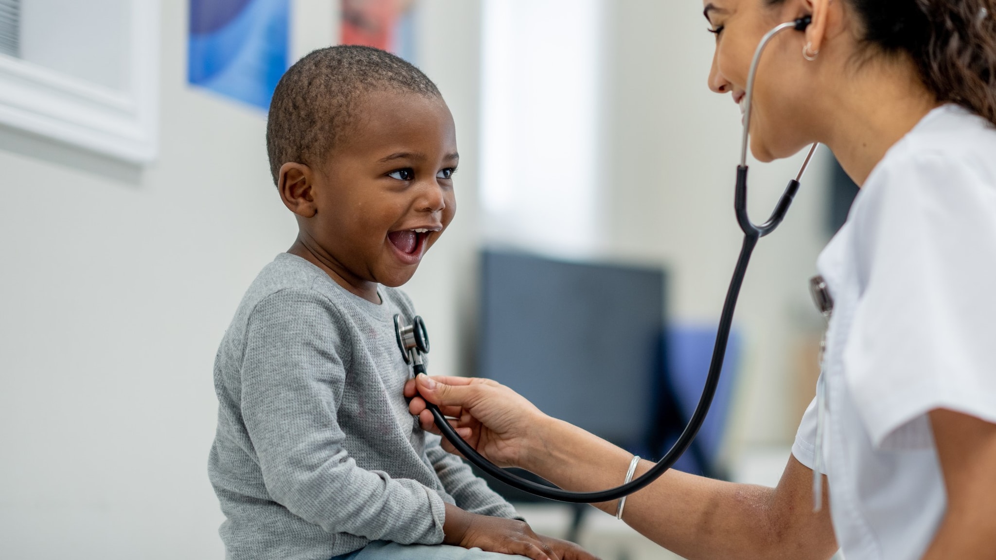 A doctor inspecting a young child with a stethoscope.