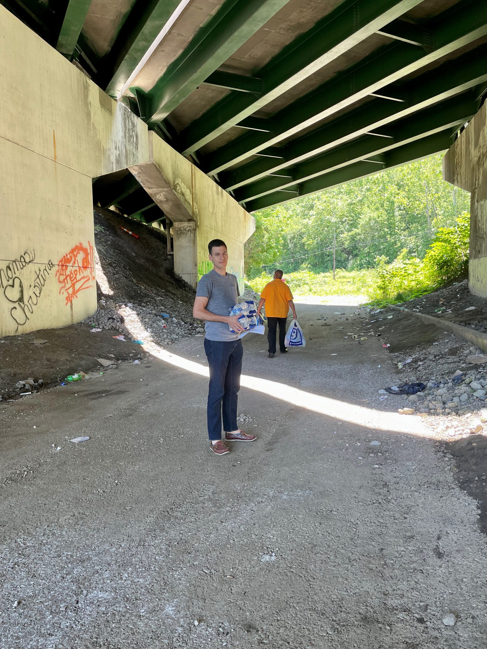 EIS officer Robert Bonacci (left) and DSTDP colleague Ken Myers (right) carrying water, food, and clothing supplies as they conduct outreach to people experiencing homelessness during an HIV outbreak among people who inject drugs in Kanawha County, West Virginia in June 2021.