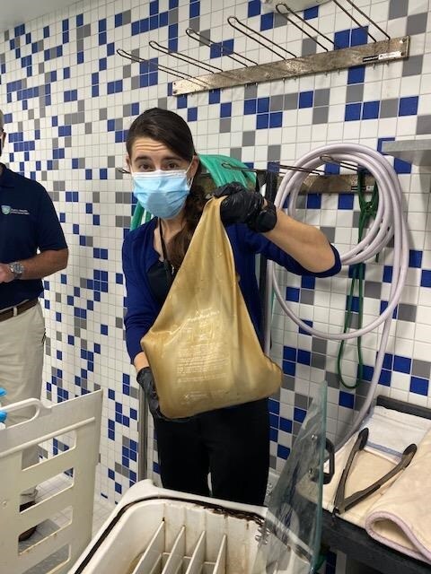 EIS officer Erin Ricketts holds up a bag from a malfunctioning hydrocollator during an environmental investigation of a respiratory illness in August of 2021.