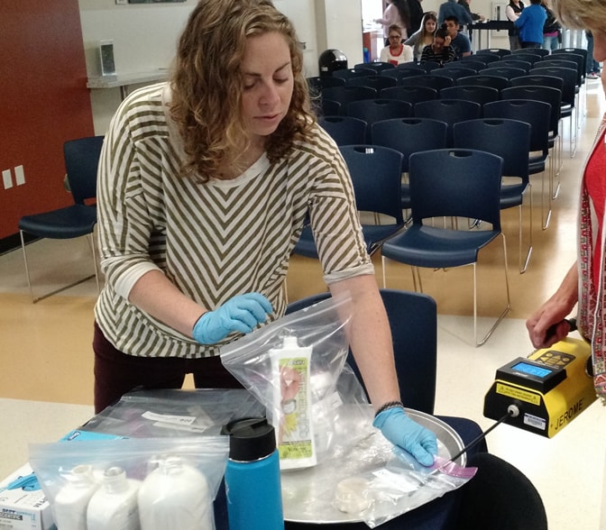 Rebecca Laws, PhD, MPH, EIS Class of 2016, tests levels of mercury in skin creams at Binational Health Week at the Mexican Consulate in Sacramento, California. 