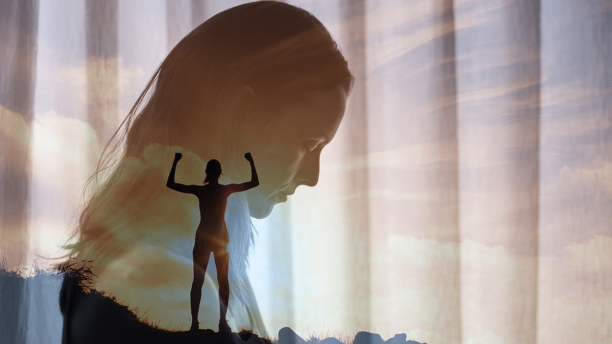 Faded close-up of sad woman, superimposed over triumphant woman silhouette at top of a mountain.