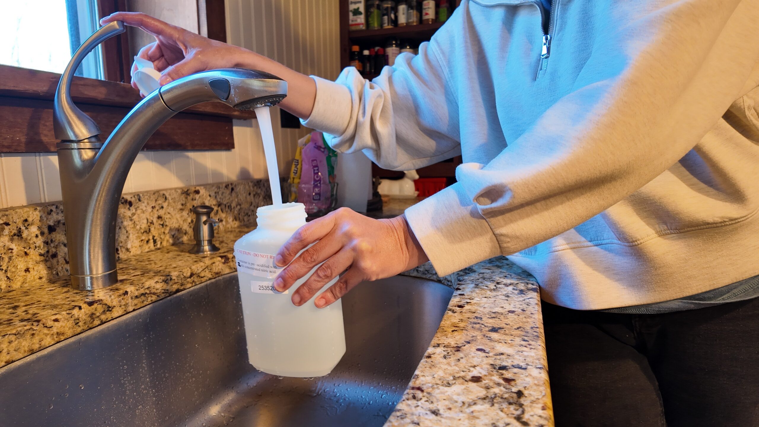 Professional fills water sample from faucet.