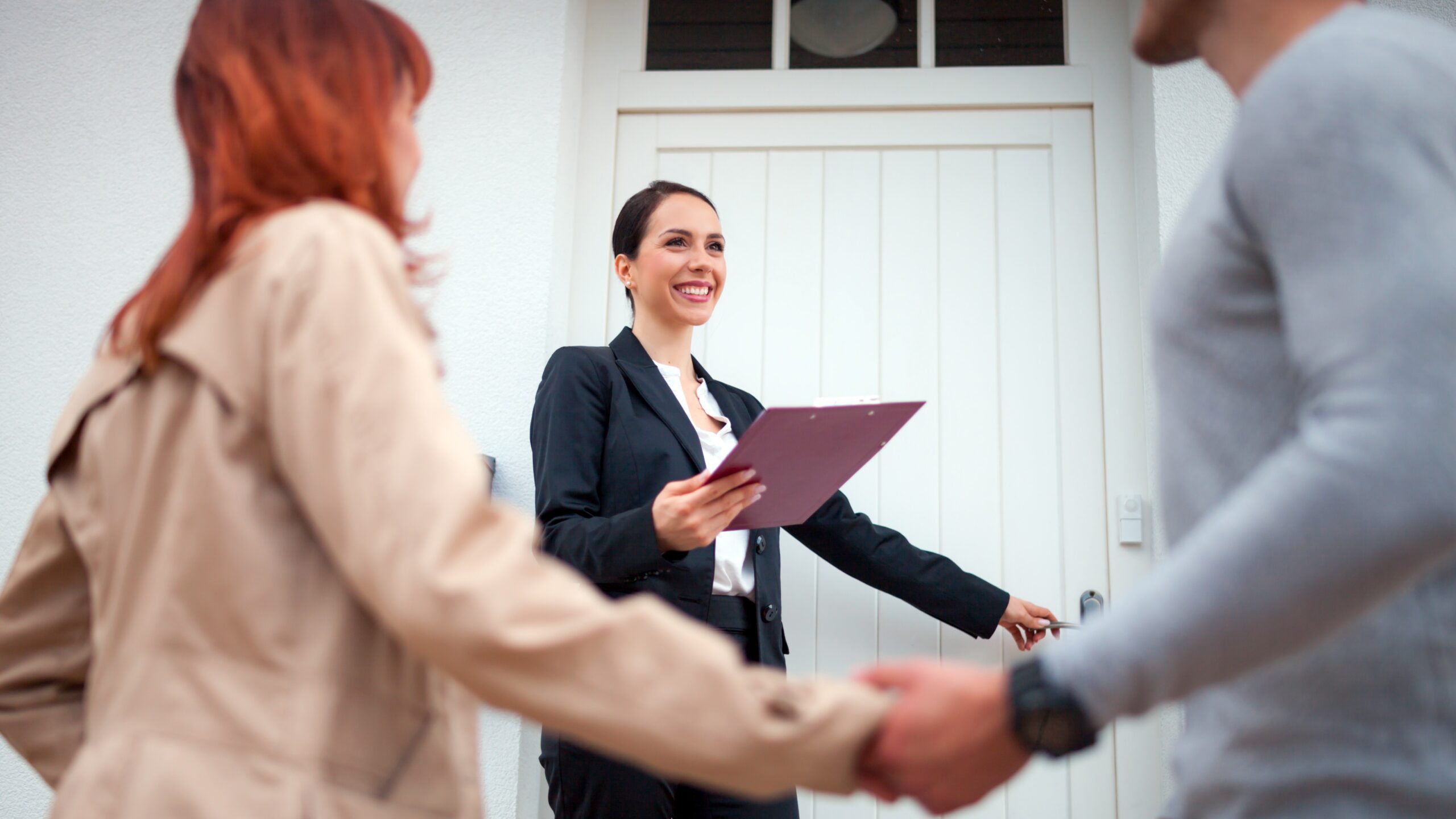 Real estate professional in front of a home with homebuyers