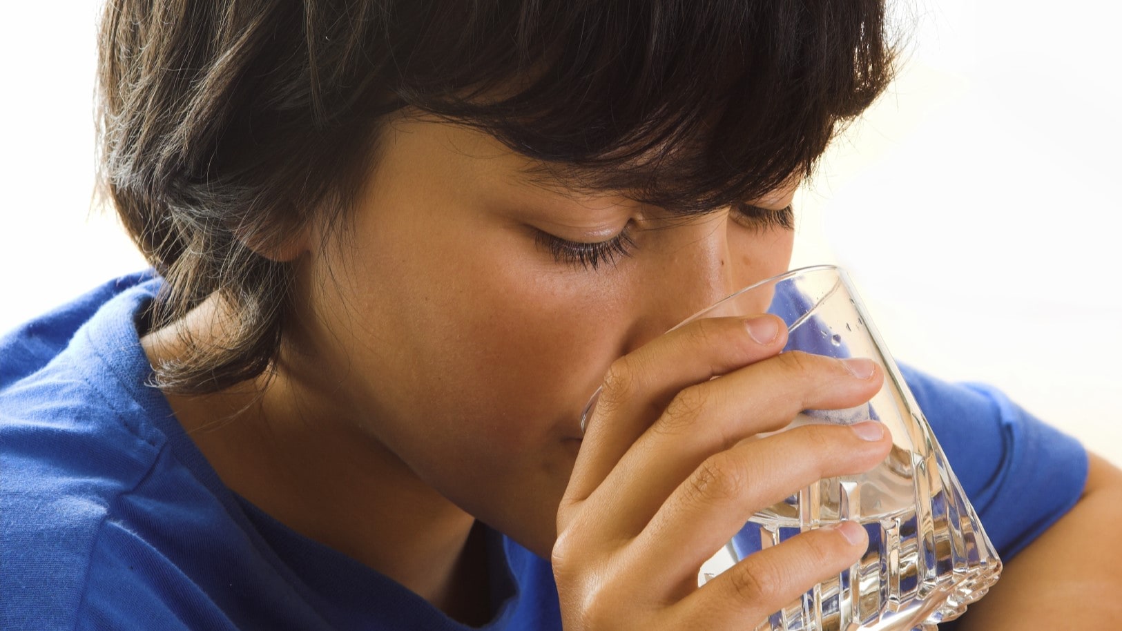 Young boy drinking a glass of water.