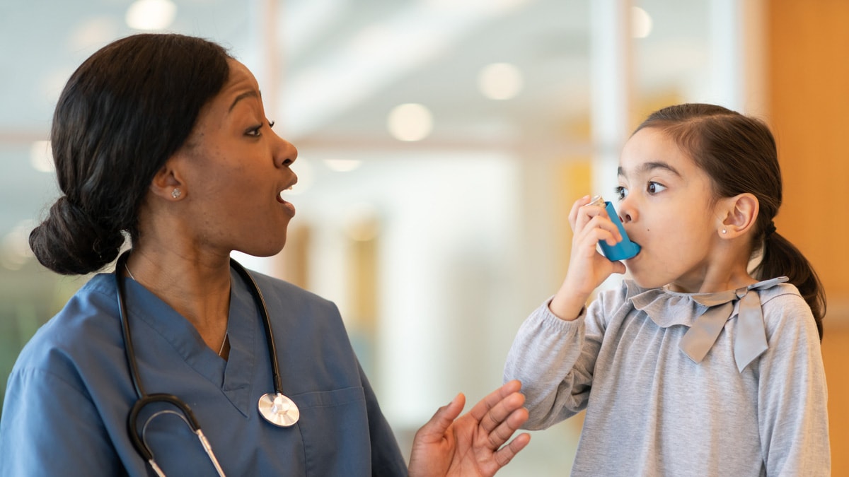 Health care worker assisting young girl using an inhaler