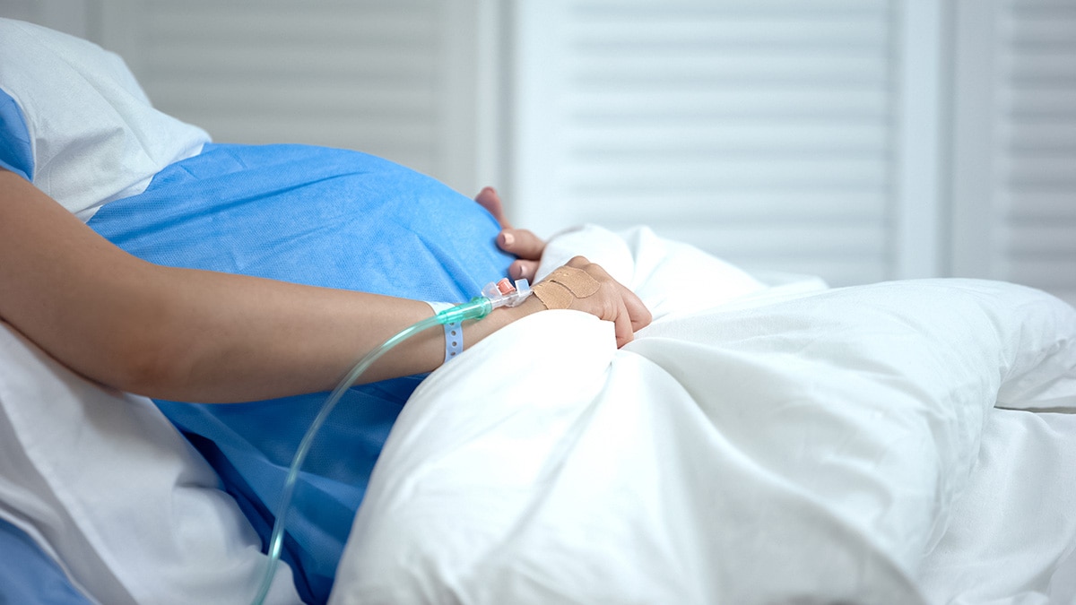 Close-up view of pregnant woman's belly while in a hospital bed