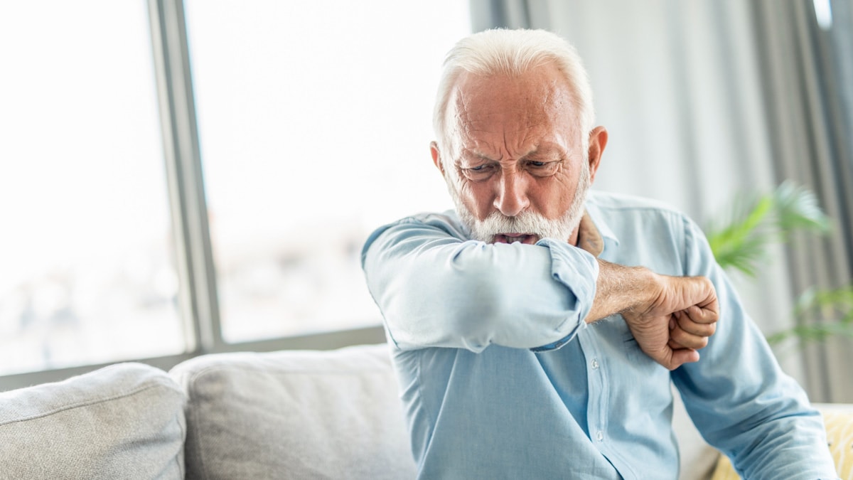 Elderly man coughing into his elbow