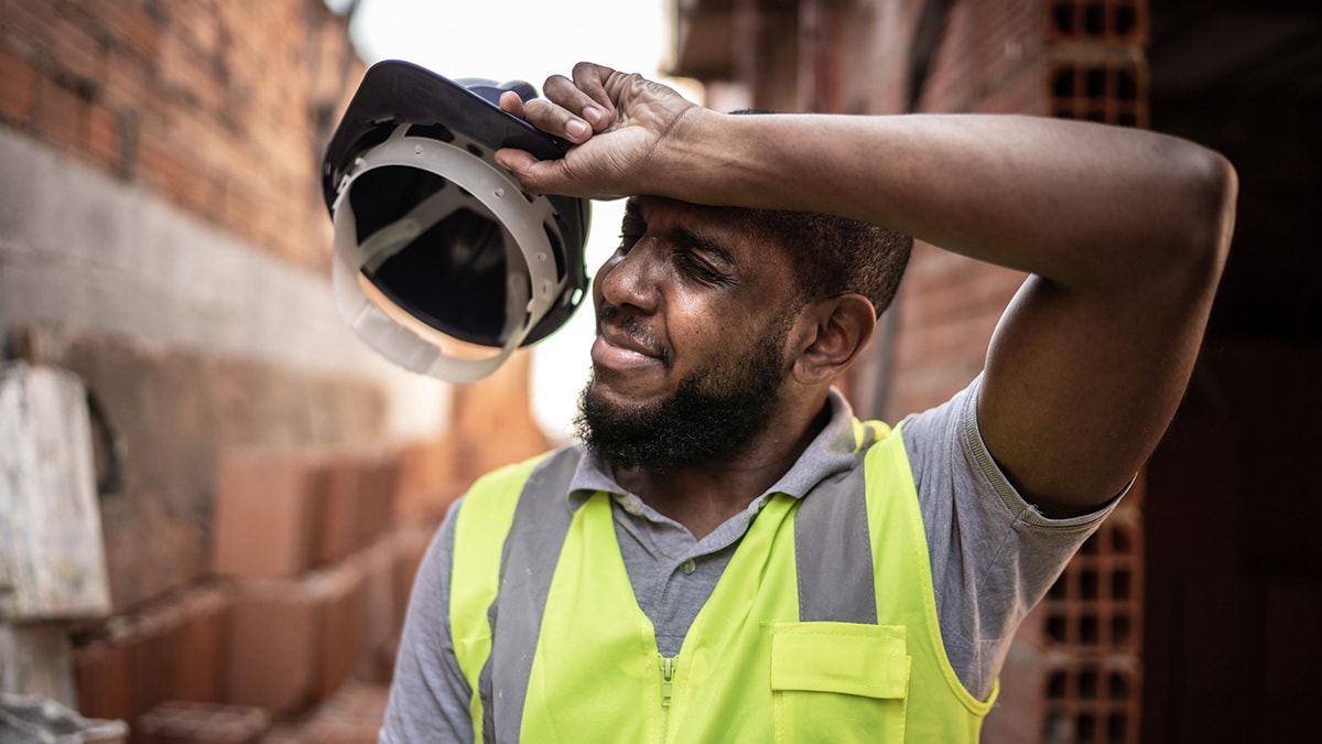 Bearded construction worker in reflective vest wiping his brow