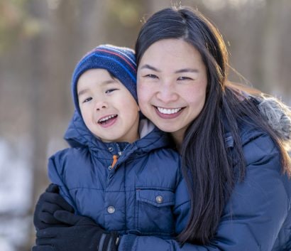 Mom hugs her son while spending time outside in the winter