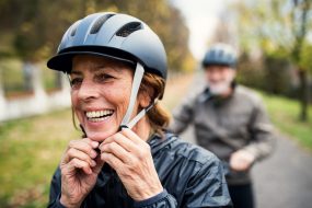 A person adjusts a helmet before getting on a bike.