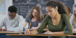 African American teen girl writing in class