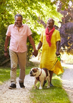 Older Black Couple Walking with a Dog and Laughing