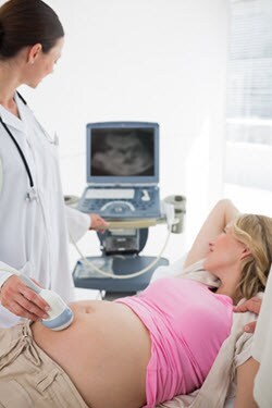una profesional de salud realizando un ultrasonido para una mujer embarazada.