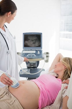 una profesional de salud realizando un ultrasonido para una mujer embarazada.