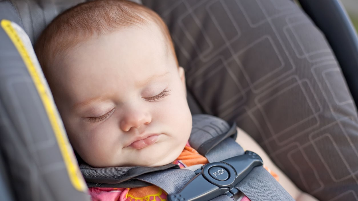 Baby asleep in a car seat.