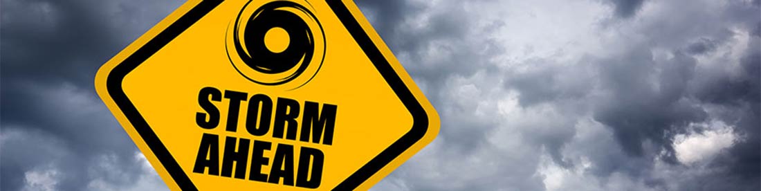 Una señal de tráfico amarilla con nubes oscuras detrás de él y un ícono de un huracán y las palabras "Tormenta por delante" significan precaución