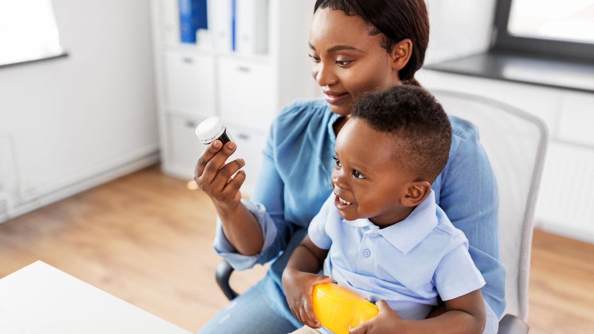 African American mother reading medication label with young child in her lap
