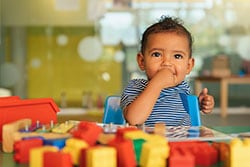 Baby putting hand in mouth and playing with toys