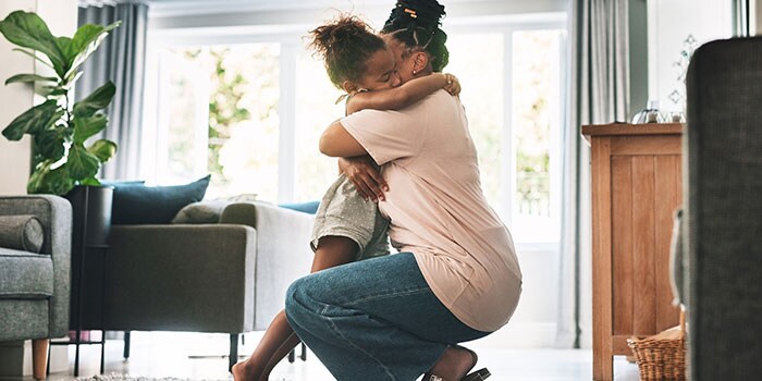 Parent and child hugging each other in the home.