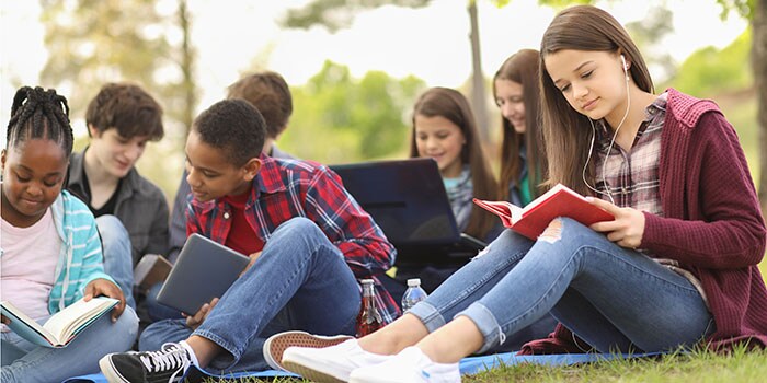Group of youth sitting outside reading