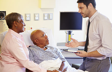 elderly couple talking to doctor in a hospital