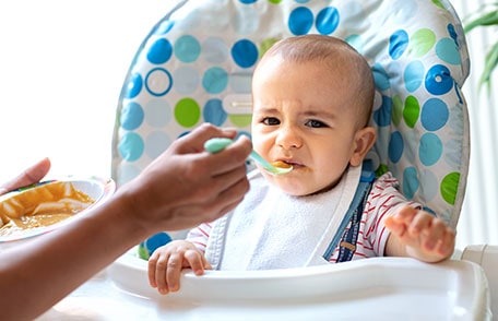 A fussy baby eating in high chair