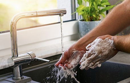 Soapy hands under faucet