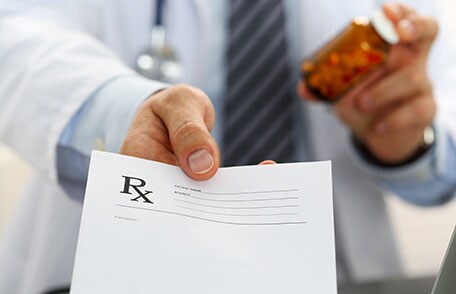 A doctor holding pills and a prescription