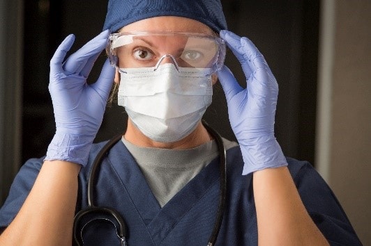 Trabajadora de atención médica usando mascarilla, guantes y protección para los ojos
