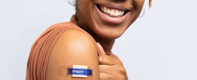 mujer con un apósito en el brazo y el hashtag #CombateLaInfluenza después de vacunarse
