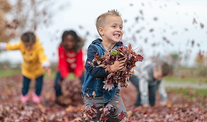 Niños jugando con las hojas al aire libre durante el otoño.