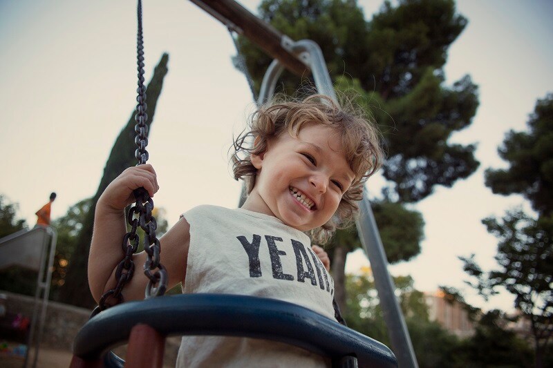 Un niño pequeño sonriendo en un columpio