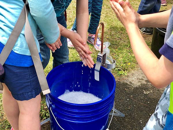 jóvenes lavándose las manos en un balde de 5 galones