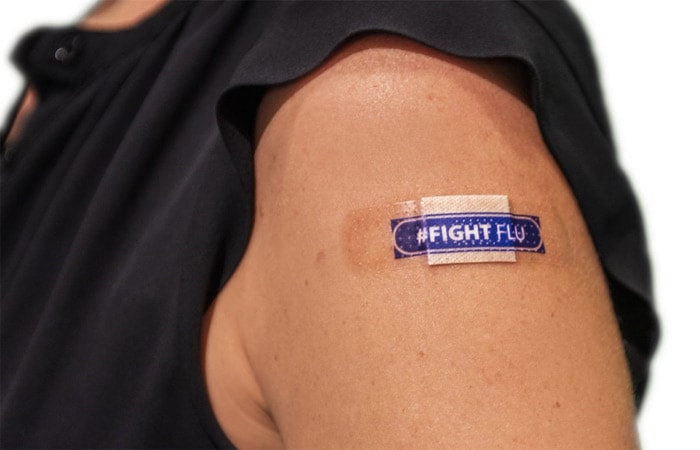 un brazo con un apósito que dice #CombateLaInfluenza