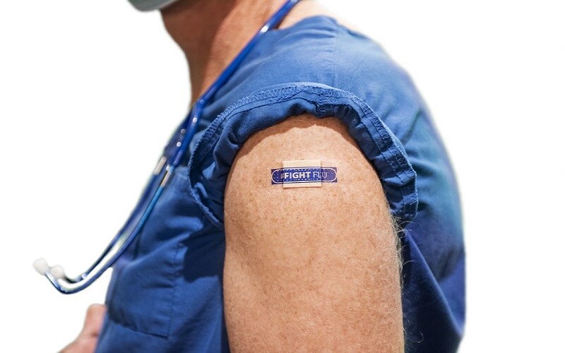 Doctor with a blue bandaid that says "Fight Flu" after getting a flu vaccine