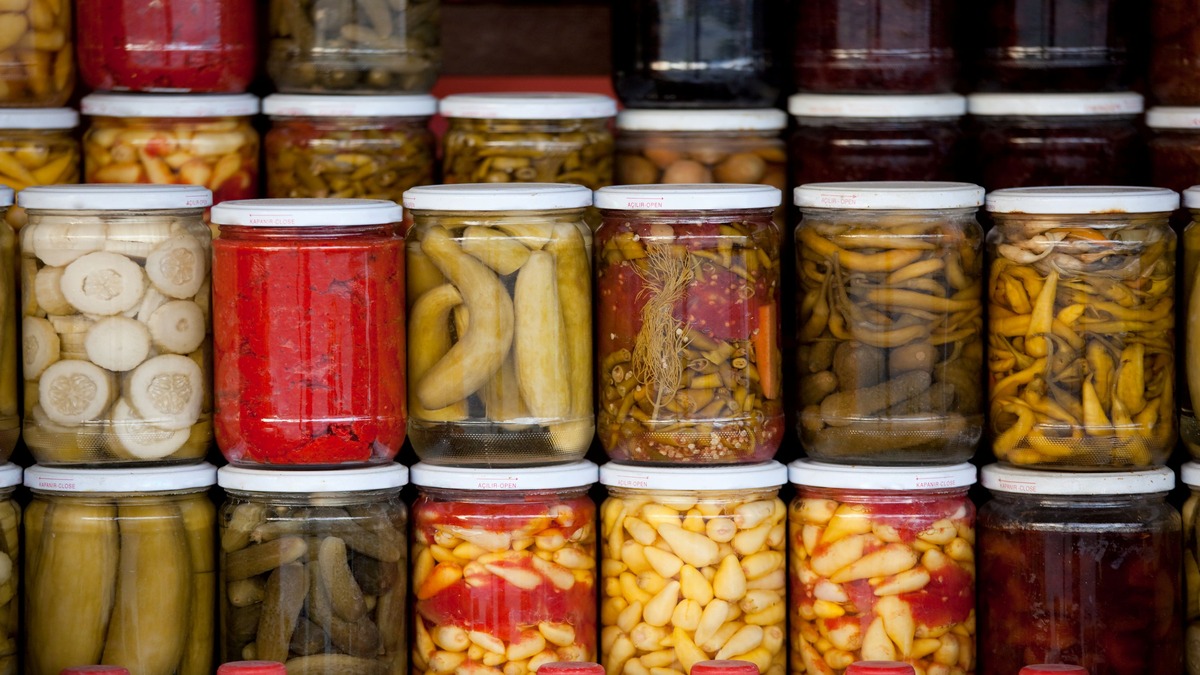 Various home canned vegetables in glass jars stacked together