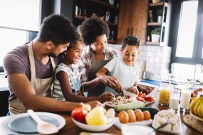 Familia afroamericana feliz preparando comida saludable juntos en la cocina
