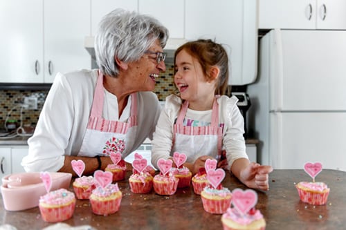 Grandmother and grandchild making valentine cupcakes