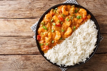 Serving of shrimp Etouffee with vegetables and sauce served with rice closeup in a plate. Horizontal top view
