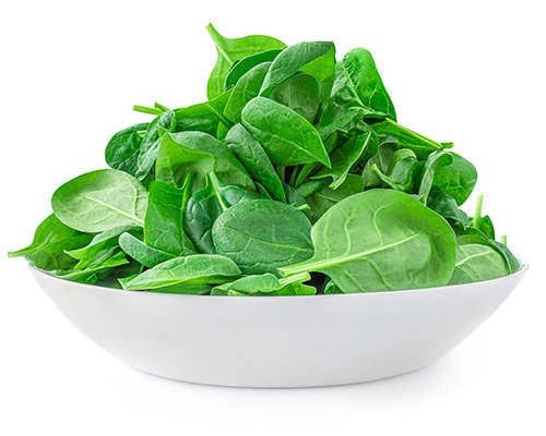 Leafy greens in a white bowl over a white background